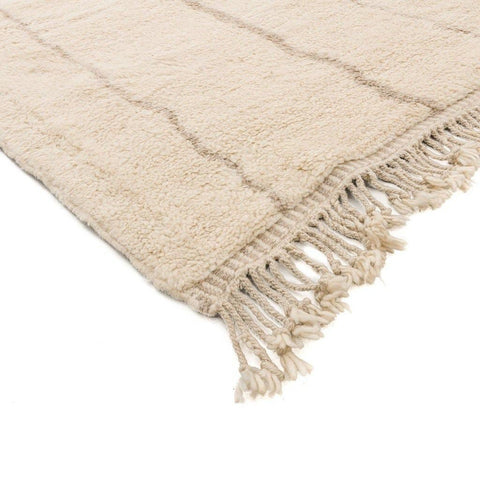 Side view highlighting the woven texture and fringe detail of the beige striped Moroccan rug.