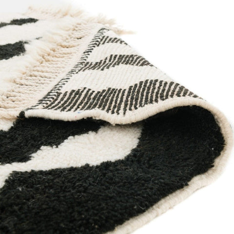 Close-up detail of the black and cream striped Beni Ourain Moroccan rug highlighting its patterned fabric.