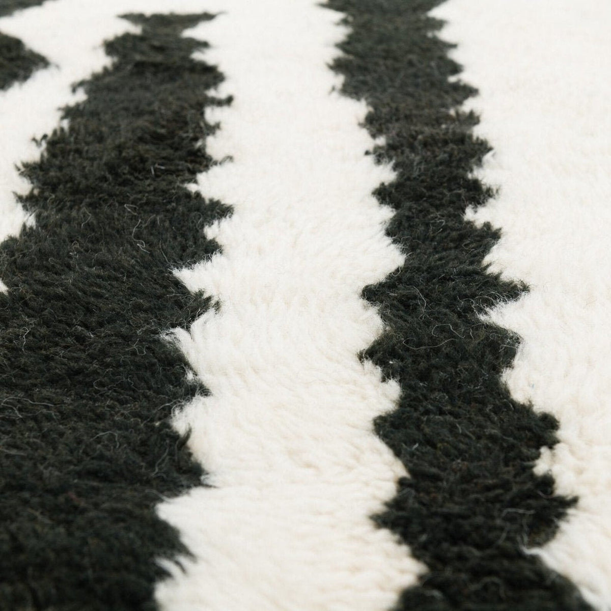 Close-up detail of the black and cream striped Beni Ourain Moroccan rug with a zigzag pattern and textured surface.
