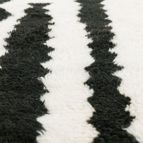 Close-up detail of the black and cream striped Beni Ourain Moroccan rug with a zigzag pattern and textured surface.