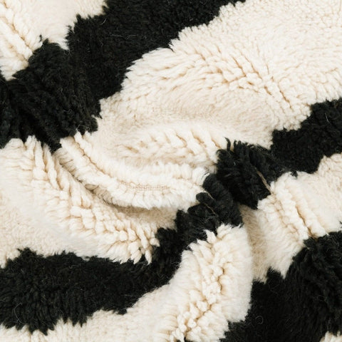 Close-up detail of the black and cream striped Beni Ourain Moroccan rug showcasing its textured surface.