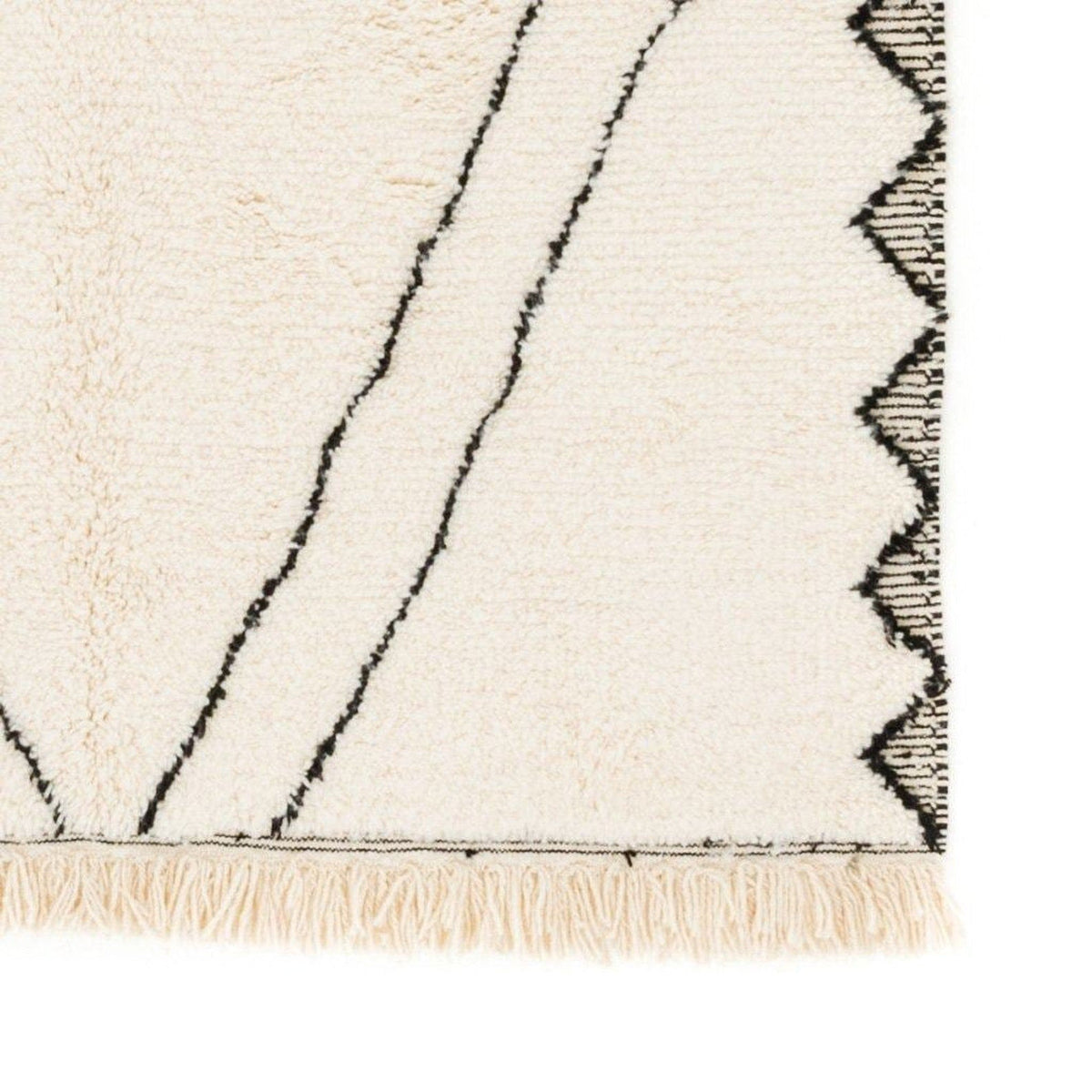 Close-up detail of the black and white Moroccan rug featuring a corner design and fringe edges.