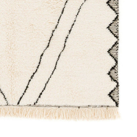 Close-up detail of the black and white Moroccan rug featuring a corner design and fringe edges.