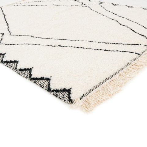 Close-up detail of the black and white Moroccan rug featuring geometric patterns and fringe edges.