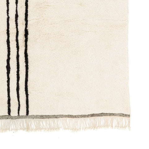 Close-up view of a black and white striped rug with fringe edges.