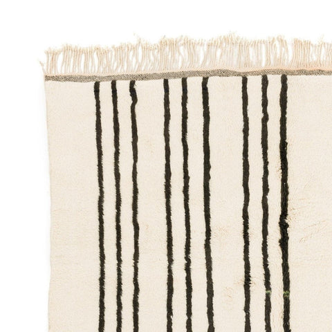 Detail close-up of a black and white striped area rug featuring a fringed edge.