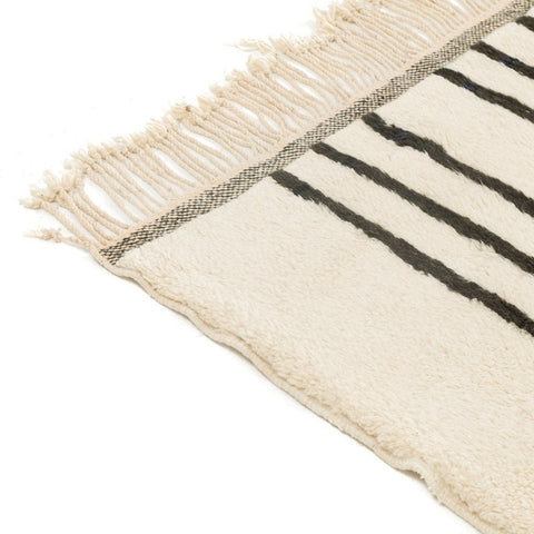 Close-up view of a black and white striped rug highlighting its fringe edges.