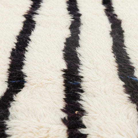 Detail close-up showcasing the soft texture of a black and white striped area rug.