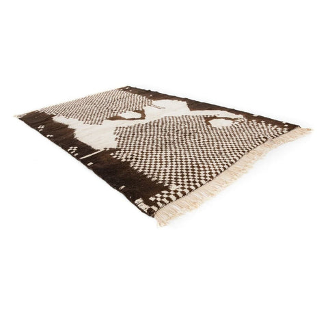 Side view of a tribal area rug featuring black and white colors and fringed edges.