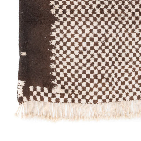 Close-up showing fringe detail and checkered pattern on the rug.