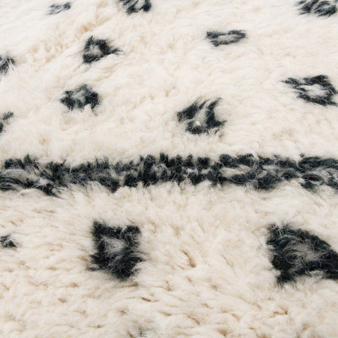 Close-up detail of the ivory geometric tribal area rug highlighting its black tribal pattern.