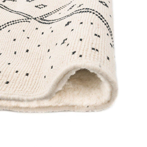 Close-up detail of the ivory geometric tribal area rug featuring its black tribal design.