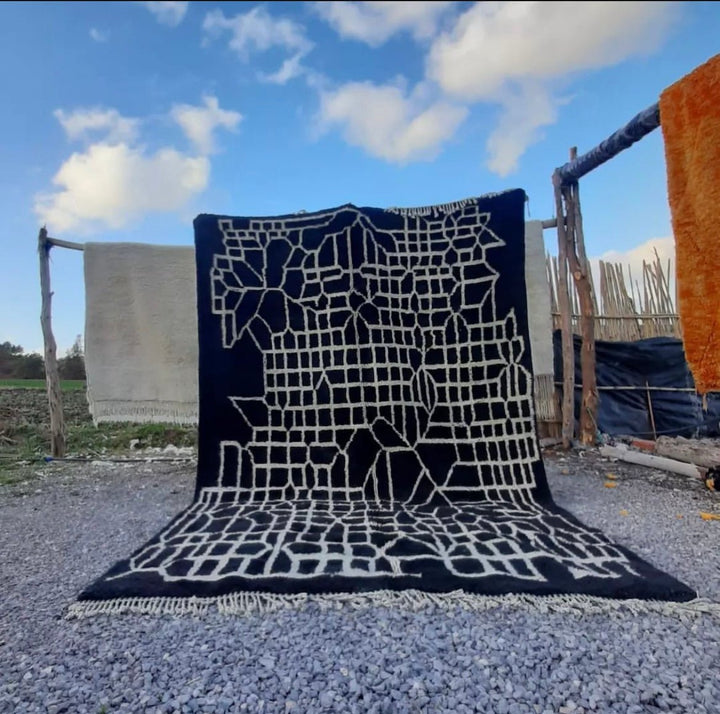 Lifestyle shot of a black Moroccan Berber rug with geometric patterns in a natural setting.