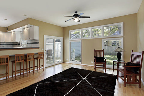 Lifestyle shot of the black Moroccan rug in a living room setting with brown and beige tones.