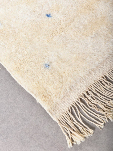 Detail close-up of the blue and yellow rug featuring fringe detail.