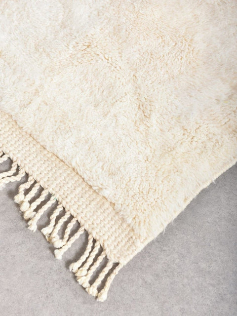 Detail close-up of the beige rug with black accents and textured surface.