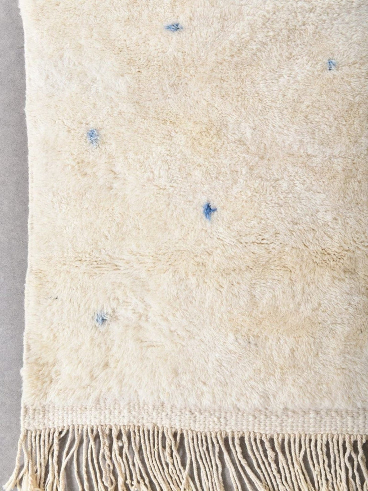Detail close-up of the beige rug with blue accents and decorative patterns.