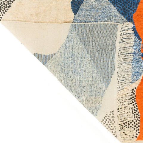 Detail view of the edge of the blue, cream, and orange abstract Moroccan rug with woven texture.