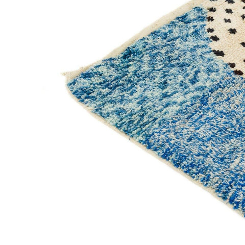 Close-up detail of the colorful corner of the blue, cream, and orange abstract rug.