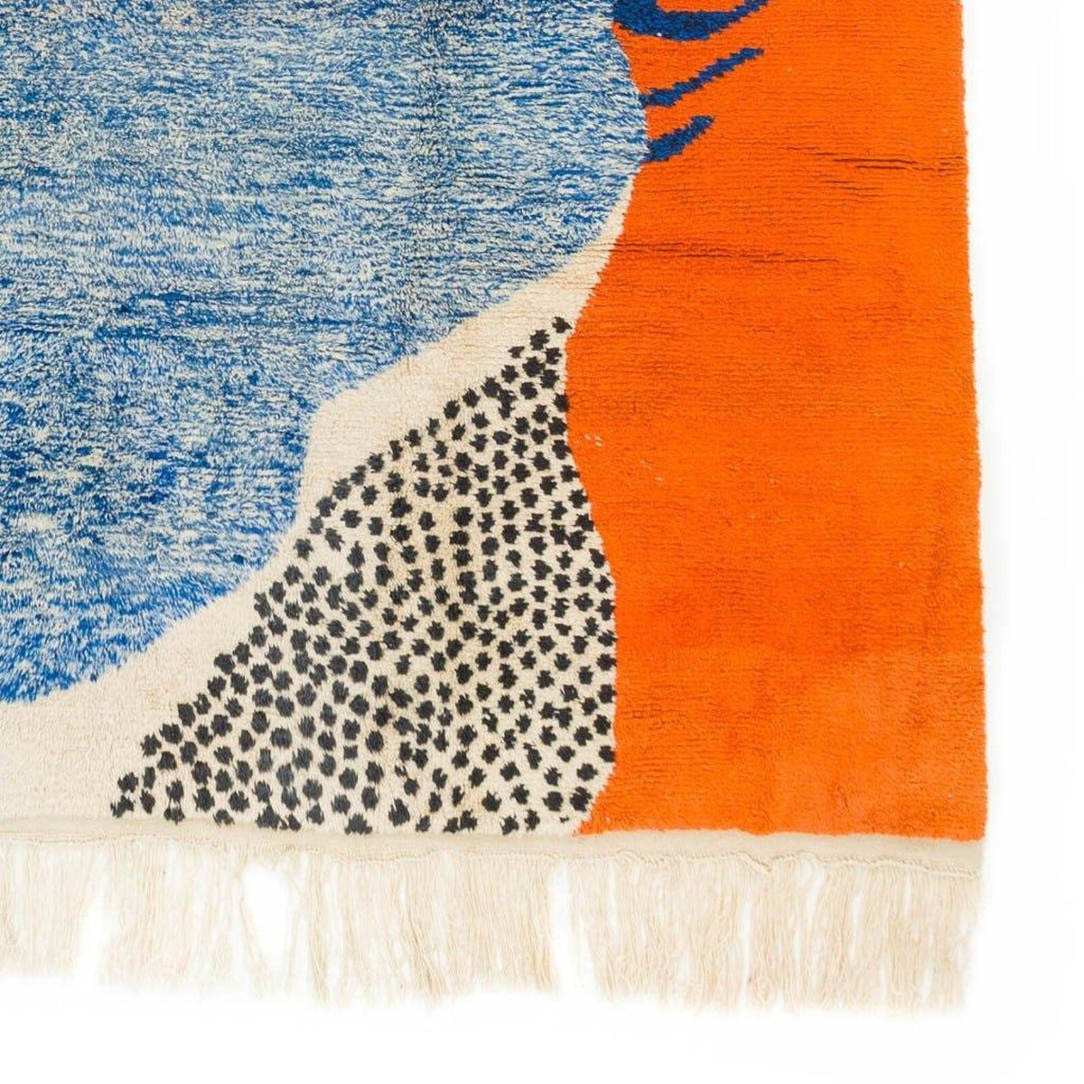 Close-up detail of the blue and orange rug with fringe edges and bold design.