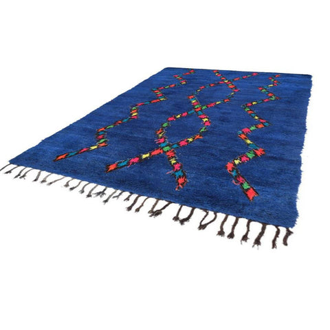 Side view of a blue Moroccan rug showcasing an abstract Berber design and fringed edges.