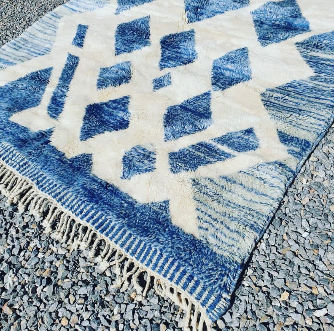 Detail shot highlighting the fringe edges and geometric pattern of the blue Moroccan rug.