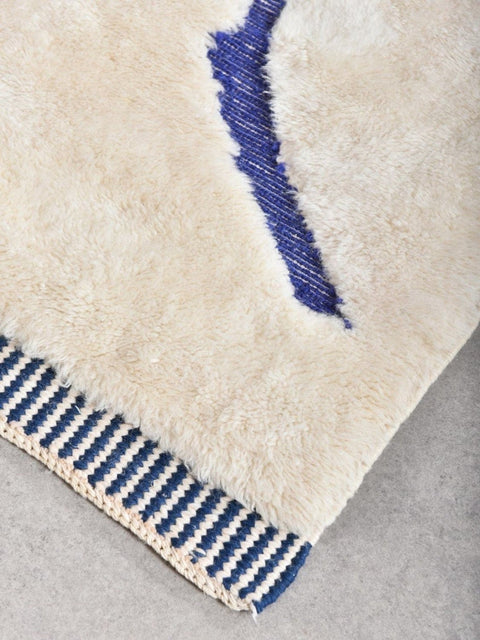 Close-up detail of the textured pattern on a blue and cream Moroccan rug.