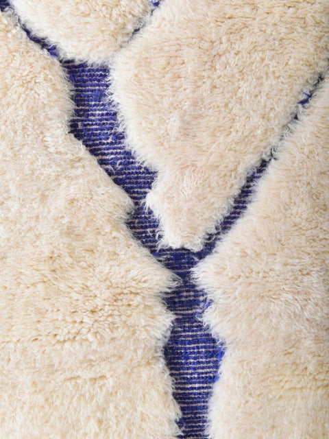 Detail view of the underside of a blue and cream rug with a woven pattern.