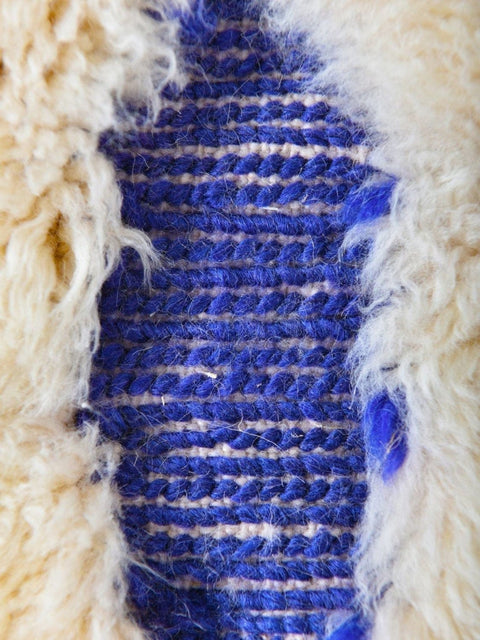 Detail view of a blue and cream rug showcasing a textured pattern.