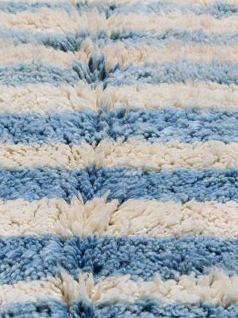 Close-up detail of the textured fibers of a blue striped Beni Ourain Moroccan rug.