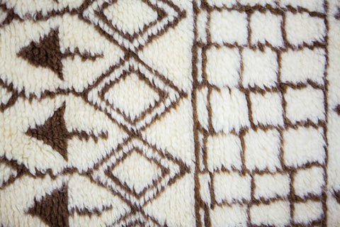 Close-up detail of the Moroccan rug's diamond pattern in black and off-white with a textured surface.