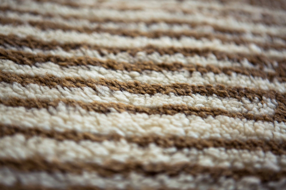 Detail shot of the striped pattern on the Moroccan rug, featuring beige and white colors.