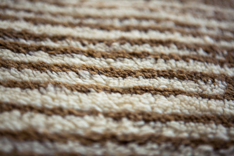 Detail shot of the striped pattern on the Moroccan rug, featuring beige and white colors.