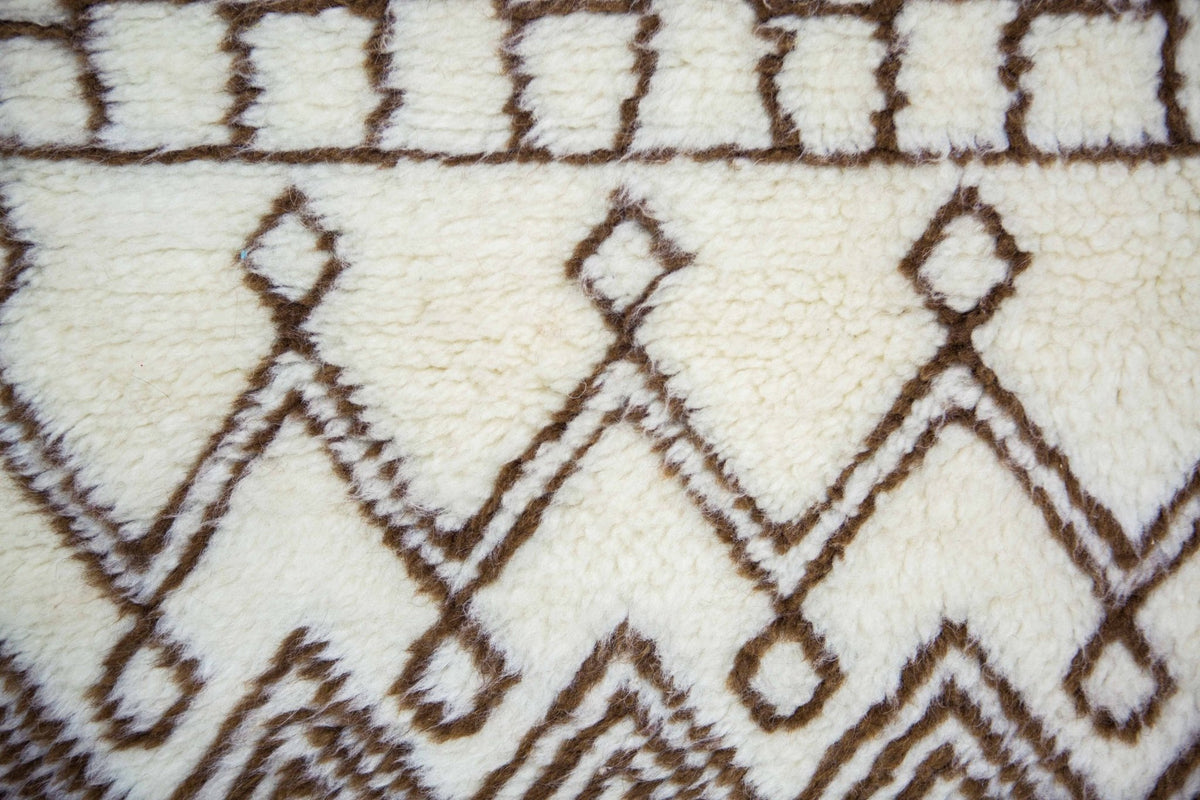 Close-up detail of the Moroccan rug displaying geometric designs in black and off-white on a textured surface.