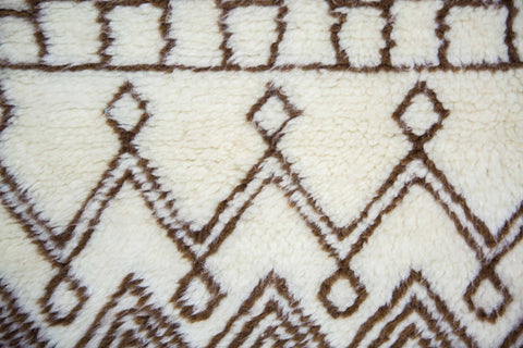 Close-up detail of the Moroccan rug displaying geometric designs in black and off-white on a textured surface.