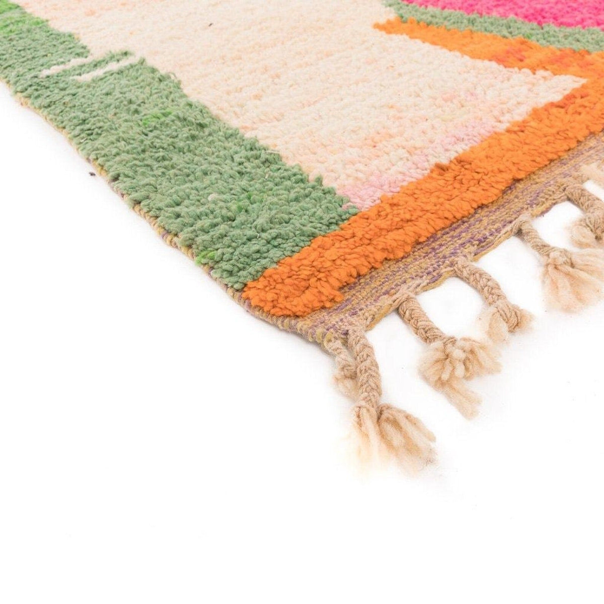 Close-up detail of the colorful rug with fringe edges and geometric patterns in pink, green, and beige.