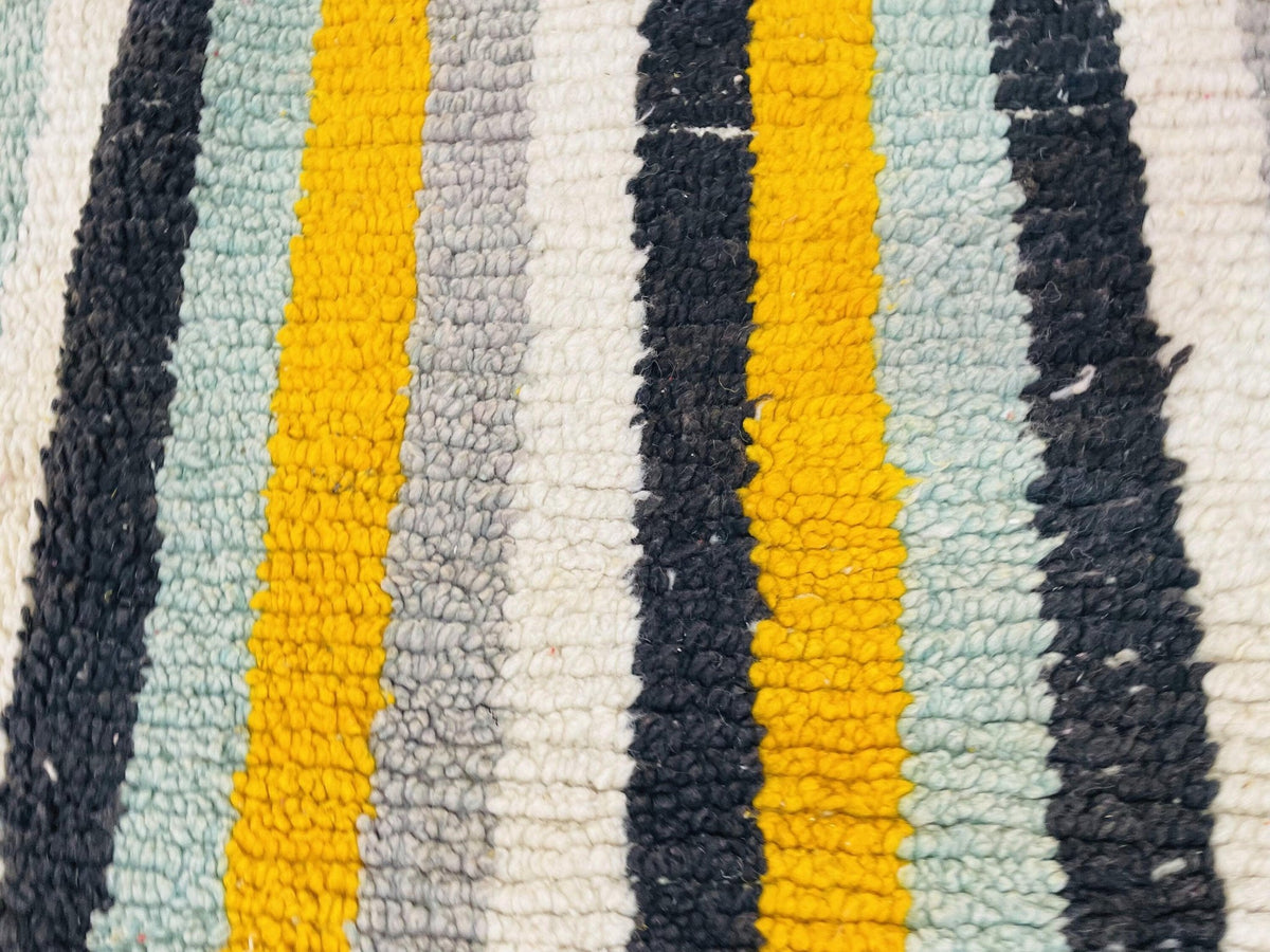Detail close-up of a striped design Moroccan rug in blue and yellow.