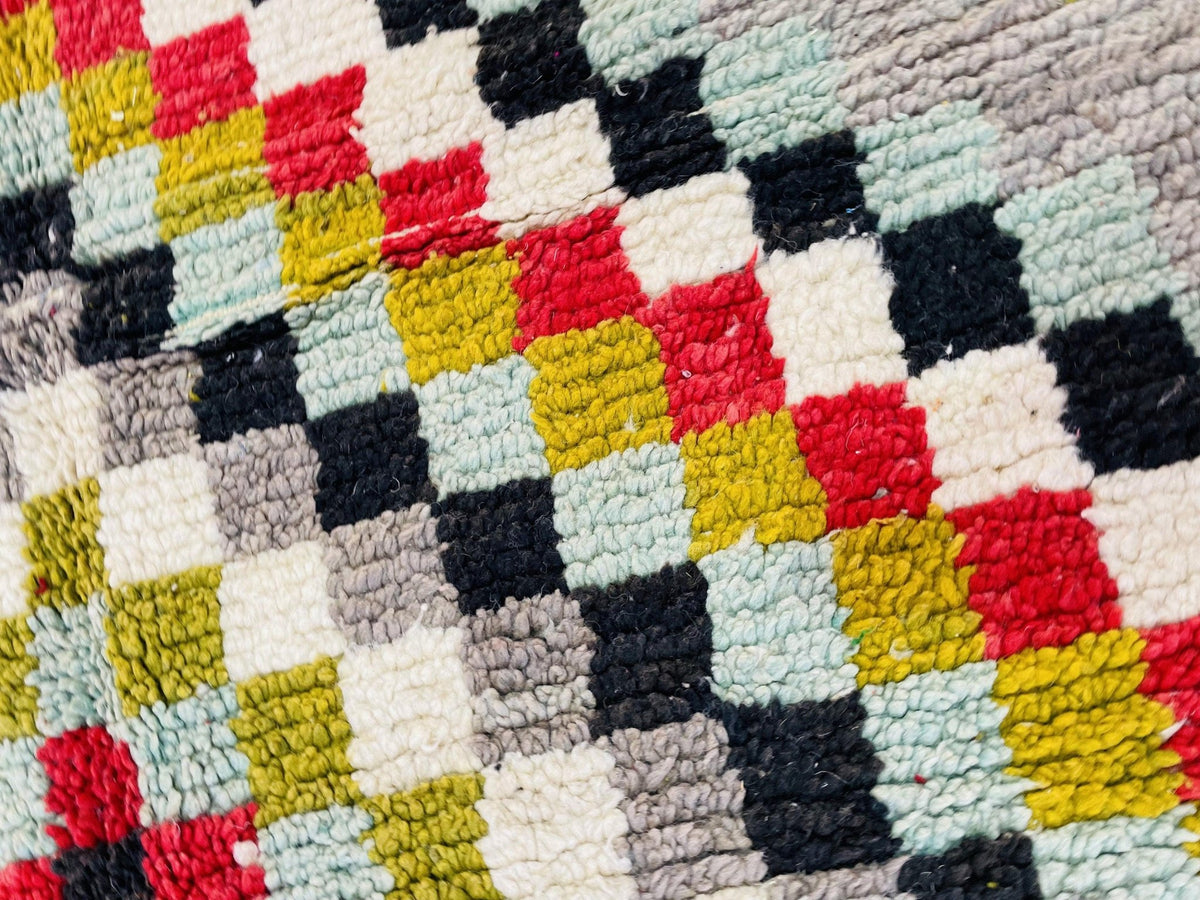 Detail close-up of a checkerboard patterned Moroccan rug in red, yellow, and black.