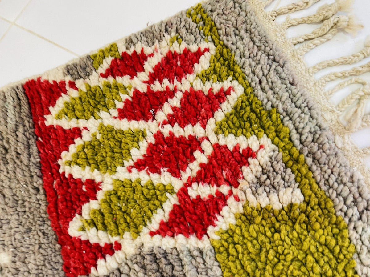 Detail close-up of a Moroccan rug displaying a geometric pattern in red and green.