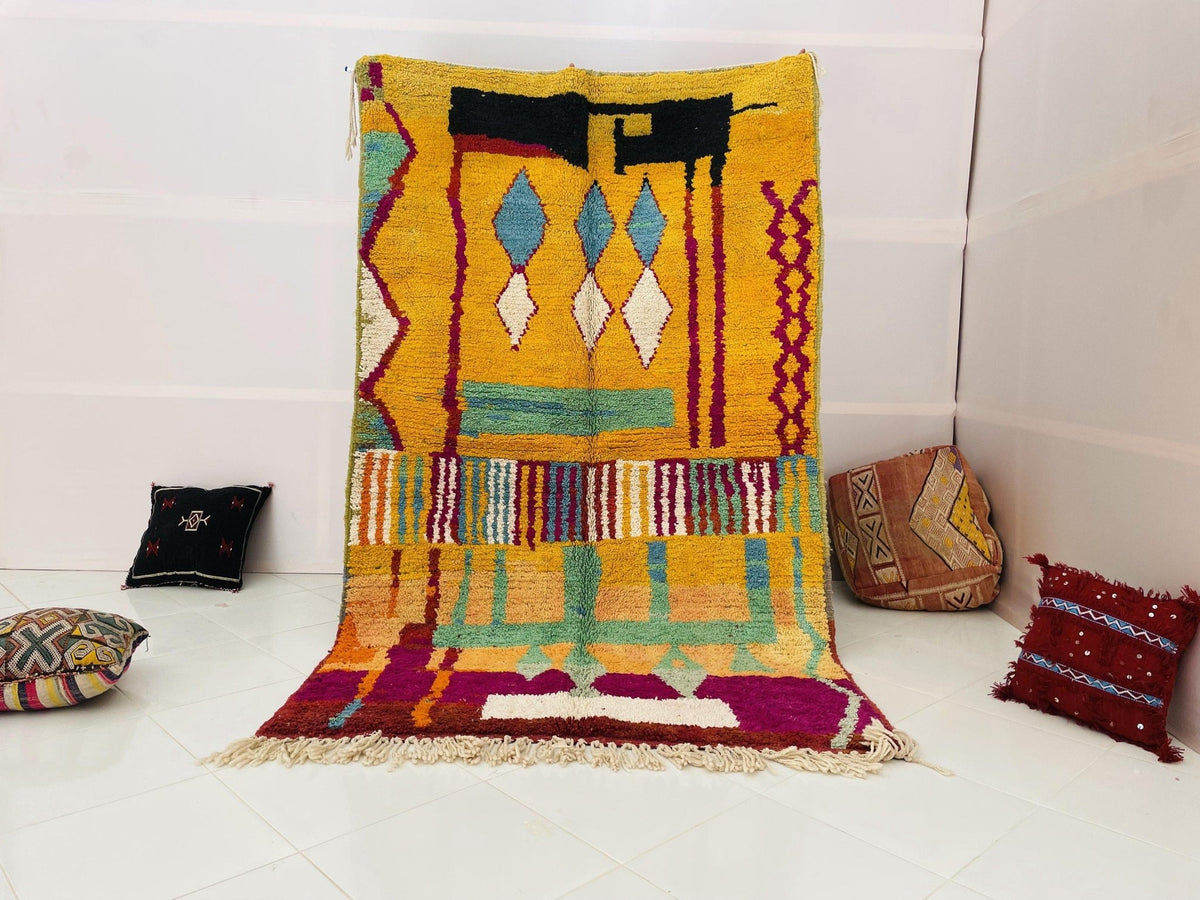 Lifestyle shot of a colorful Moroccan rug featuring geometric patterns on a white background.