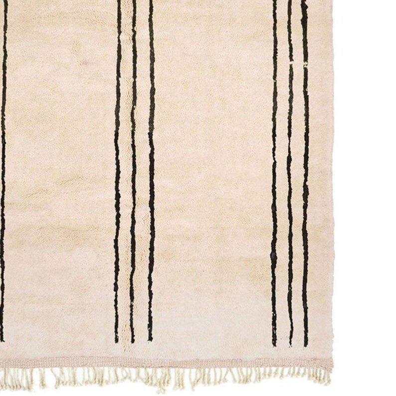 Detail view of the beige striped Moroccan rug with fringe edges on a white background.