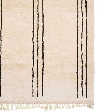 Detail view of the beige striped Moroccan rug with fringe edges on a white background.