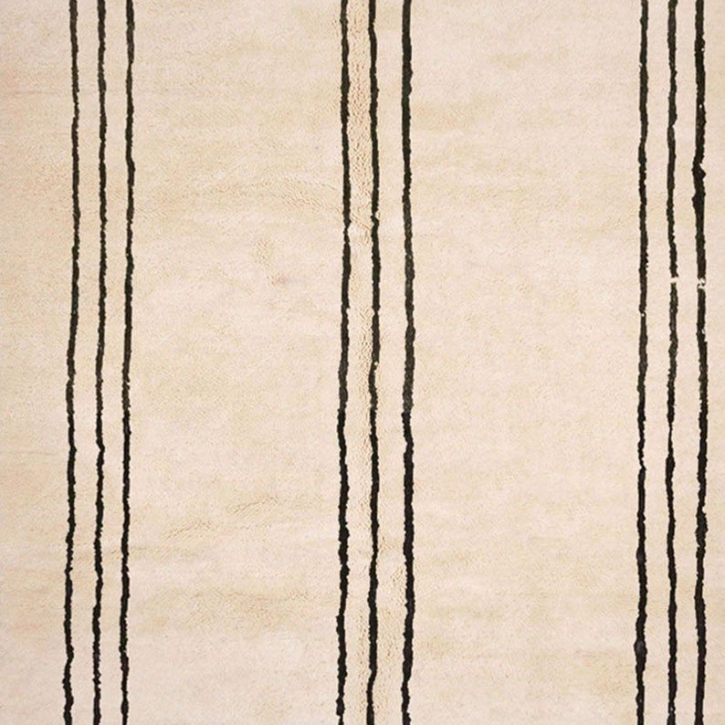 Side view of the beige striped Moroccan rug showing fringe edges on a white background.