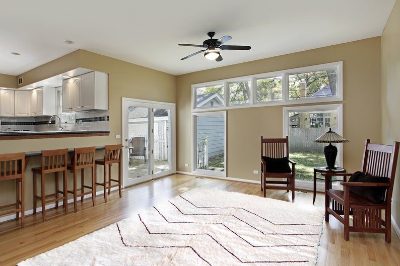 Lifestyle shot of the cream striped Beni Ourain Moroccan rug in a living room setting with wooden furniture.
