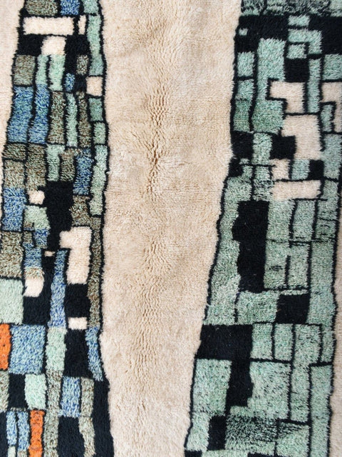 Detail shot of the rug edge with fringe detail and layered texture in beige, blue, and orange.