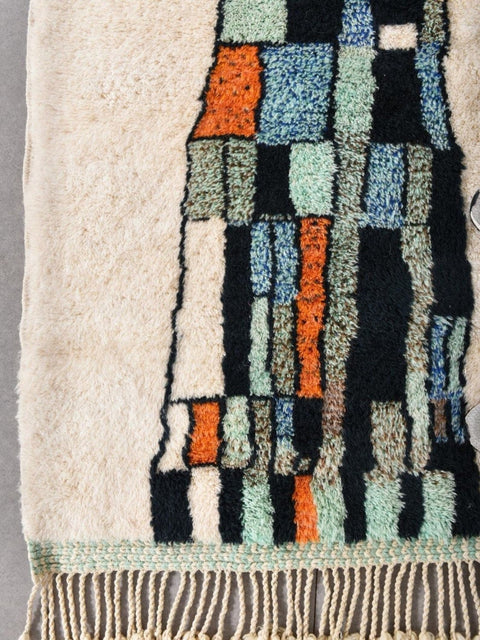 Close-up view of the rug texture highlighting geometric patterns in beige, blue, and orange.