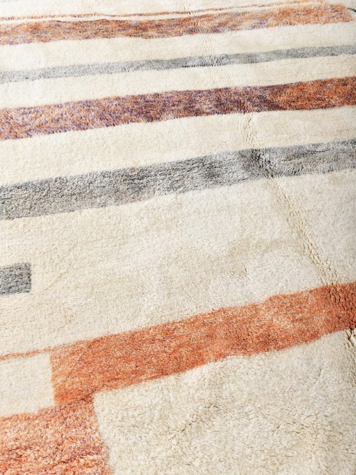 Detail close-up of a cream and orange area rug with a striped pattern and soft texture.