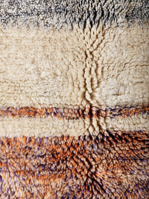 Detail close-up of a cream and orange abstract area rug with a textured surface.