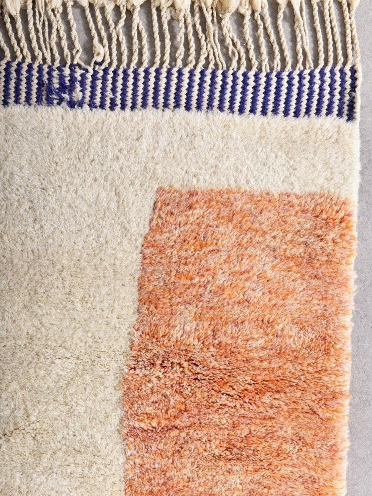 Detail close-up of a cream and orange area rug featuring a geometric design and soft texture.