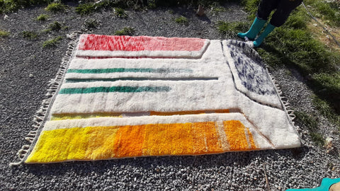 Top view of a colorful Berber rug showcasing geometric patterns in beige, orange, green, and blue.